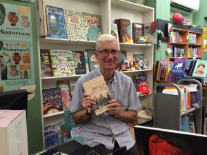 Ian Tyrrell sitting in a bookstore holding his book River Dreams