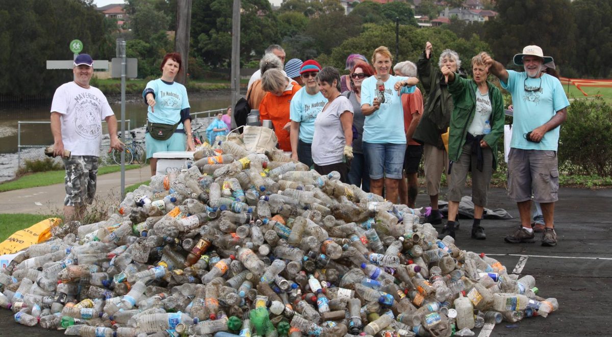 Mudcrabs members stand behind a huge pile of plastic bottles pulled out from the river