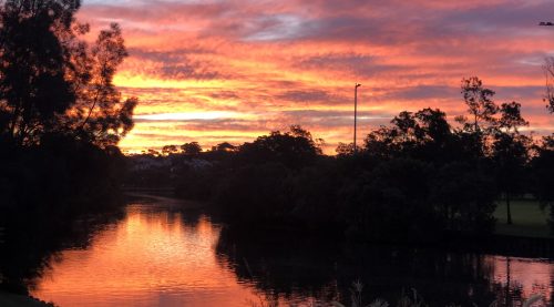 Orange, pink and purple tones in the sky at sunset reflecting in the Cooks RIver